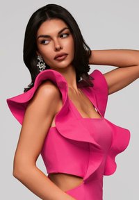 Robe rose avec des manches volantes, découpe à la taille et design ajusté. Texture lisse avec une finition mate. Boucles d'oreilles florales audacieuses.