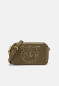 Ποδιά χιαστί από δέρμα σε ελαιόχρωμο με λευκά ραφές. Διαθέτει φερμουάρ κλεισίματος, λογότυπο στο μπροστινό μέρος και λουράκι με αλυσίδα.