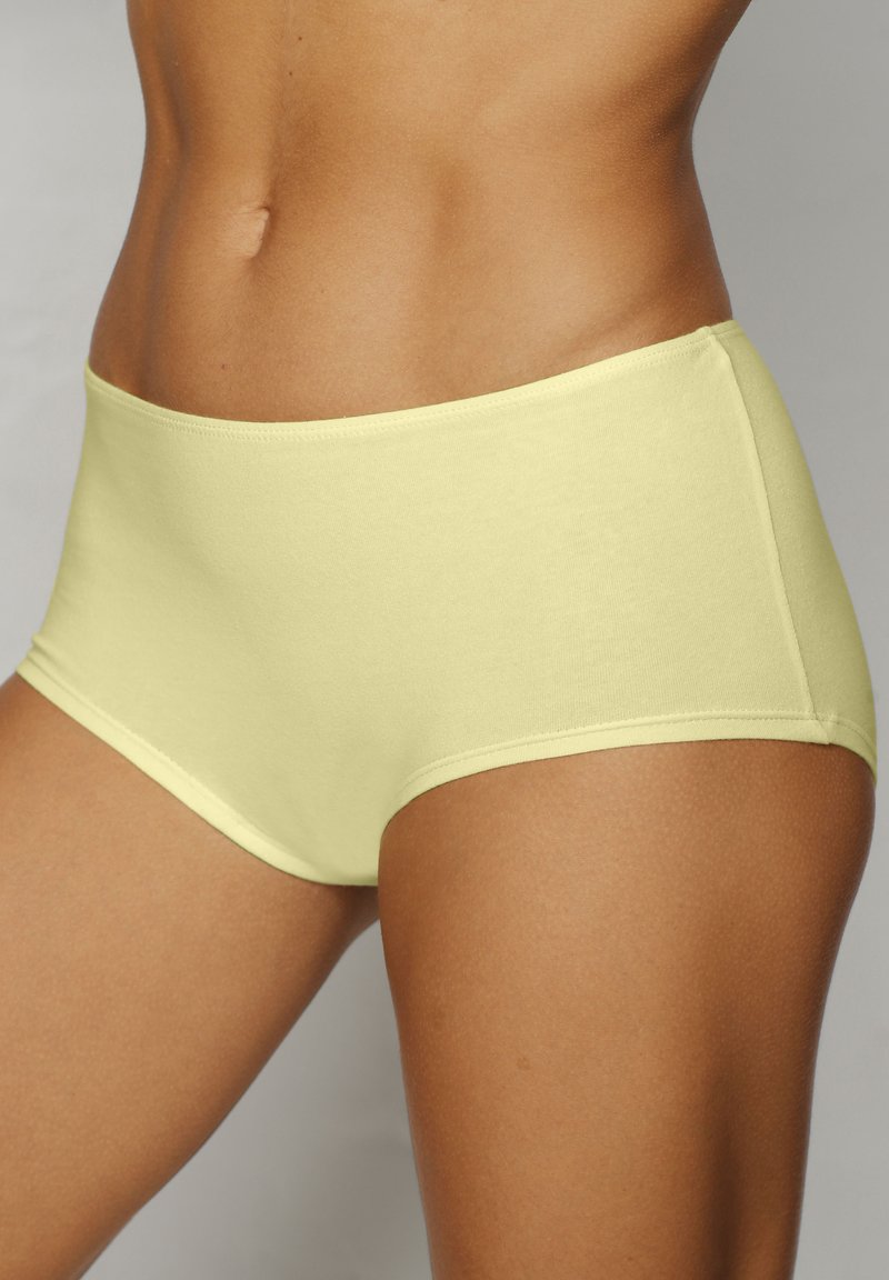 High-waisted underwear in light yellow cotton. Smooth texture, elastic waistband, and flat seams for comfort. No patterns or hardware details.