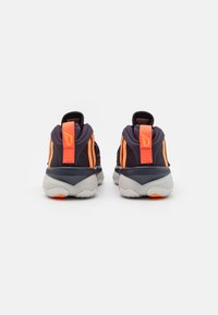 Black athletic shoes with orange accents, textured mesh upper, padded collars, and a grey sole featuring a distinct tread pattern.