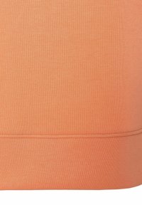 Oranje katoen stof met een gladde textuur en een rechte snit. De onderkant heeft een subtiele naaddetails. Eenvoudig ontwerp zonder patronen of accenten.