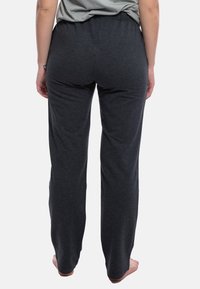 Pantaloni da sudore grigi, larghi e comodi, realizzati in un tessuto morbido e testurizzato. Presentano un elastico in vita e gambe dritte senza motivi visibili.