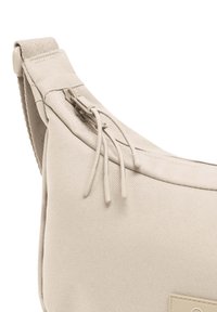 Borsa a tracolla in tessuto beige con una texture morbida, dotata di chiusura a zip e due linguette testurizzate sulla zip. Etichetta a contrasto visibile.