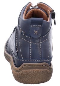 Námořnické kožené kotníkové boty s texturovanou gumovou podrážkou, kontrastním prošíváním a zipem na zadní straně. Hladká vnitřní podšívka.