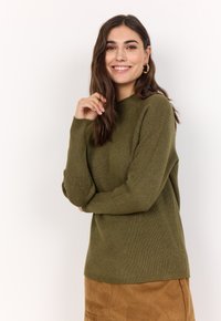 Olivgrüner gerippter Pullover mit langen Ärmeln und hohem Kragen, kombiniert mit einem braunen Wildlederrock. Glatte Textur und lässige Passform.