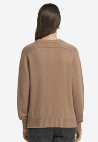 Brązowy, oversize sweter z okrągłym dekoltem, ściągaczami przy rękawach i na dolnej krawędzi. Teksturowana tkanina o gładkim wykończeniu i opadających ramionach.