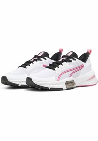 Zapatillas deportivas blancas con parte superior de malla, acentos negros, detalles en rosa y una suela texturizada. Presentan cierre de cordones y un detalle de marca metálica.