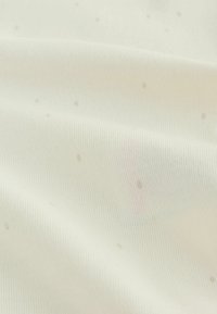 Kremasto bež tkanino z rebrastim vzorcem in majhnimi, nejasnimi pikami. Gladek tekstura s kančkom sijaja, primerna za oblačila ali oblazinjenje.