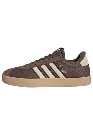 Brązowe niskie sneakersy Adidas z beżową podeszwą, białymi paskami po bokach i logo Adidas przy sznurowadłach.