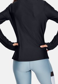 Svart långärmad träningströja med avslappnad passform, i kombination med ljusblå leggings som har mörka detaljer och en slät, elastisk textur.