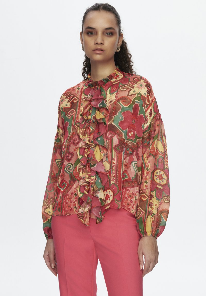 Blusa multicolor con un patrón floral, con volantes en el frente y mangas largas. Hecha de una tela ligera, con un escote alto.