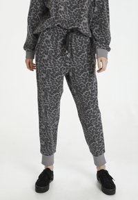 Grå leopardstribede joggere med elastisk talje, snøre og elastiske manchetter, parret med sorte platform sneakers.