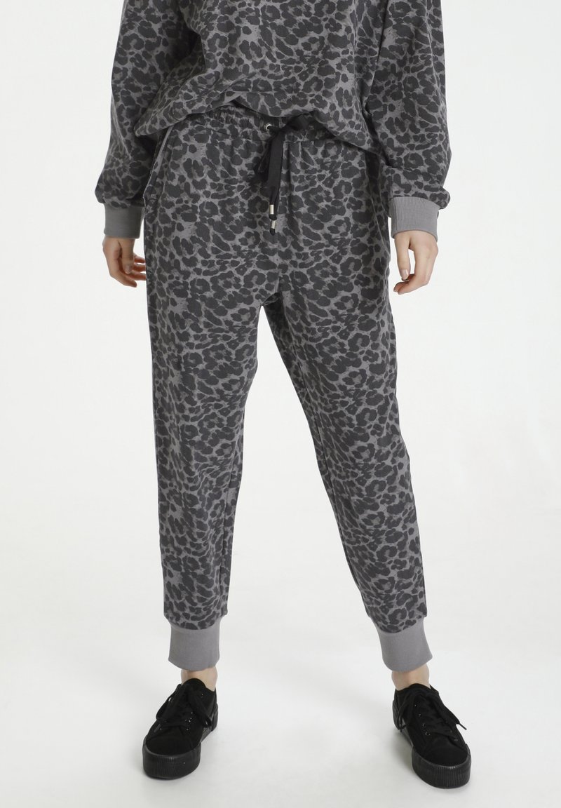 Pantalones de chándal con estampado de leopardo gris, con cinturilla elástica, cordón y puños elásticos, combinados con zapatillas negras de plataforma.