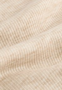 Beige ribbat tyg med fin struktur, med vertikala linjer som skapar ett subtilt mönster. Slät och mjuk yta med lätt lyster.