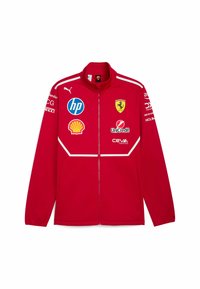 Czerwona kurtka zapinana na zamek z wysokim kołnierzem; posiada loga Ferrari, HP, Shell i innych. Gładki materiał z białymi akcentami i szwami.