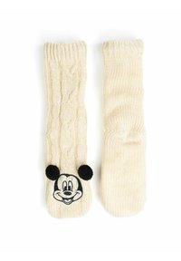 Mittens di colore crema lavorati a maglia con un motivo a treccia e un volto di Topolino ricamato in nero, completo di orecchie rotonde nere.