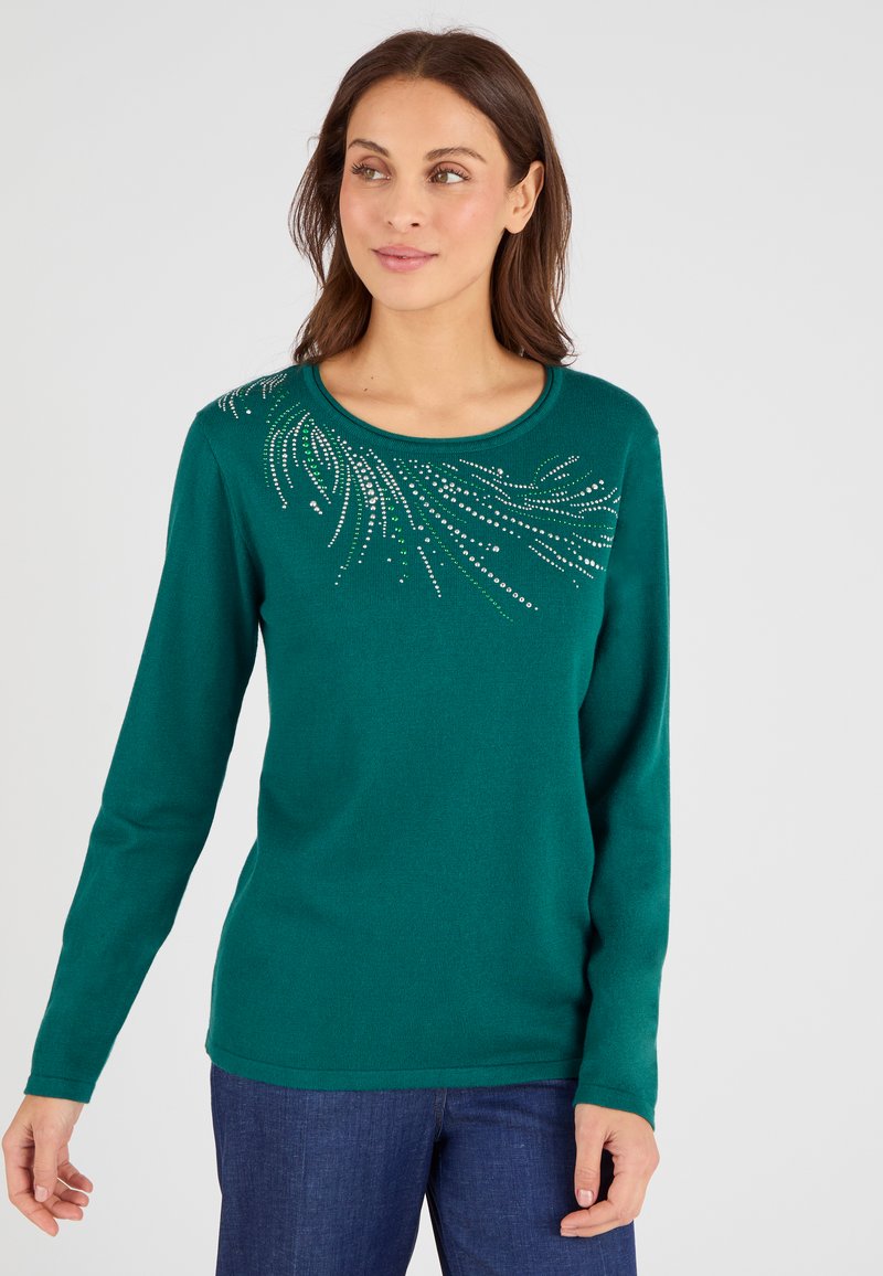 Suéter verde de manga larga con cuello redondo. Presenta acentos decorativos de cristal en un patrón en espiral en la parte superior izquierda. Textura suave.