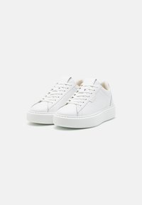 Hvite lær sneakers med flate snører, avrundet tå, hevet gummisåle og subtile sømdetaljer. Minimalistisk design uten synlige logoer.