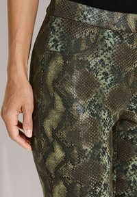 Slangenprint legging gemaakt van een gestructureerde stof in tinten groen en bruin, met een soepele tailleband en een nauwsluitend ontwerp.
