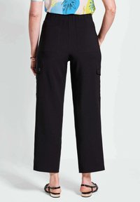 Zwarte cargo-broek met brede pijpen, grote zijzakken en een zachte textuur. Met elastische tailleband voor comfort. Gekoeld met een kleurrijke patroon top.
