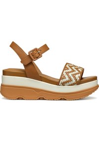 Sandalias de cuña de piel marrón con una correa trenzada, plantilla blanca y suela de goma texturizada. Cuenta con una correa ajustable en el tobillo.