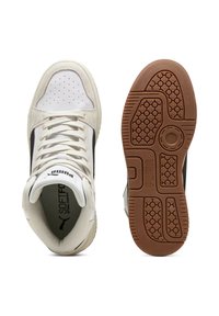 Sneakers alte con tomaia in pelle bianca, dettagli neri e punta traforata. Presentano una suola spessa in gomma e un design con lacci. Stile retrò.