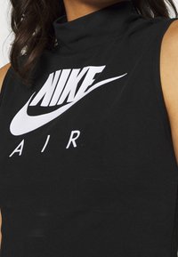 Svart ärmlös topp med hög krage som har en stor vit "NIKE AIR"-logotyp, tillverkad av slät tyg med en figurnära design.