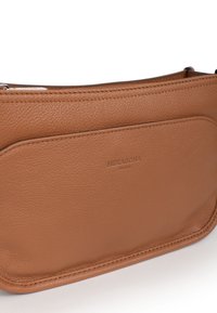 Borsa a mano in pelle marrone con una texture liscia, forma rettangolare e tasca frontale. Presenta il logo embossato "HEXAGONA PARIS" su una superficie piatta.