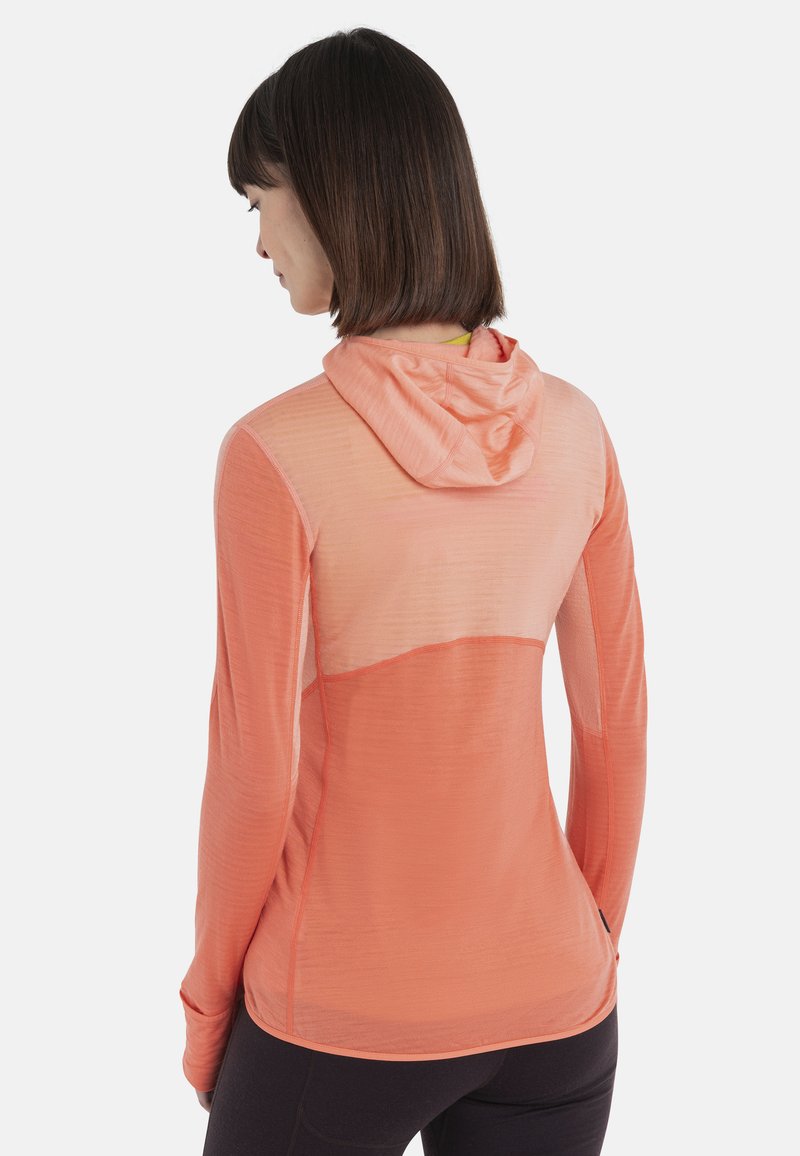 Haut de sport à capuche en tissu dégradé corail et pêche. Présente des manches longues, une texture légère et un panneau en mesh dans le dos.