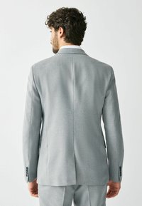 Gray suit jacket with a smooth texture, single vent at the back, and buttoned cuffs. Features a clean, tailored design.
