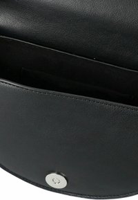 Schwarze Lederhandtasche mit offenem Deckel und sichtbarem Magnetverschluss, der ein leeres Innenfach zeigt.