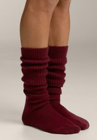 Bordeauxrode geribbelde gebreide beenwarmers met een nonchalant ontwerp, reiken boven de enkel, met een zachte textuur en een ontspannen, opgerimpeld bovenstuk.