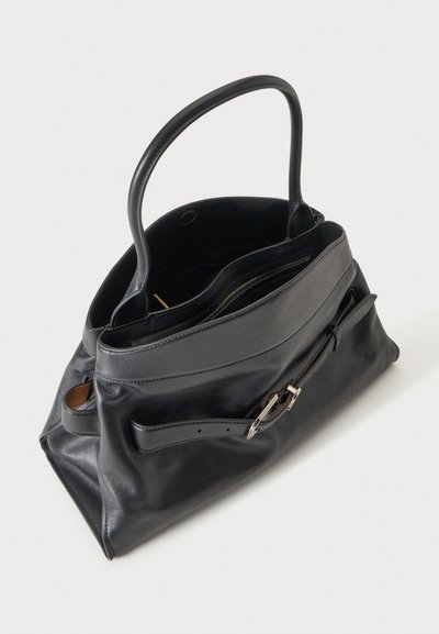 Sac à main en cuir noir avec une poignée, détail de ceinture à l'avant avec boucle argentée, et compartiment supérieur zippé, montré légèrement ouvert.
