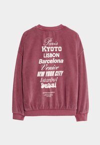 Bordowy sweter z grafiką nazw miast na plecach, z prążkowanymi mankietami i pasem, oraz luźnym krojem.
