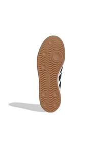 Suela de zapato de goma con textura ondulada, patrones circulares y la marca "adidas"; presenta un diseño en blanco y negro a lo largo del lateral.