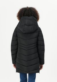 Zwarte pufferjas met een chevronpatroon, capuchon en ritszakken. Het materiaal lijkt glad met opgeblazen secties voor isolatie.