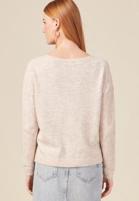 Maglione lavorato a maglia di un rosa chiaro, con una vestibilità ampia, polsini a coste e scollatura rotonda. Motivo a spina di pesce testurizzato sulle maniche.