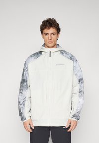 Lightweight hooded jacket in white with gray marble-patterned sleeves, featuring a full zipper and logo accents. Textured fabric.