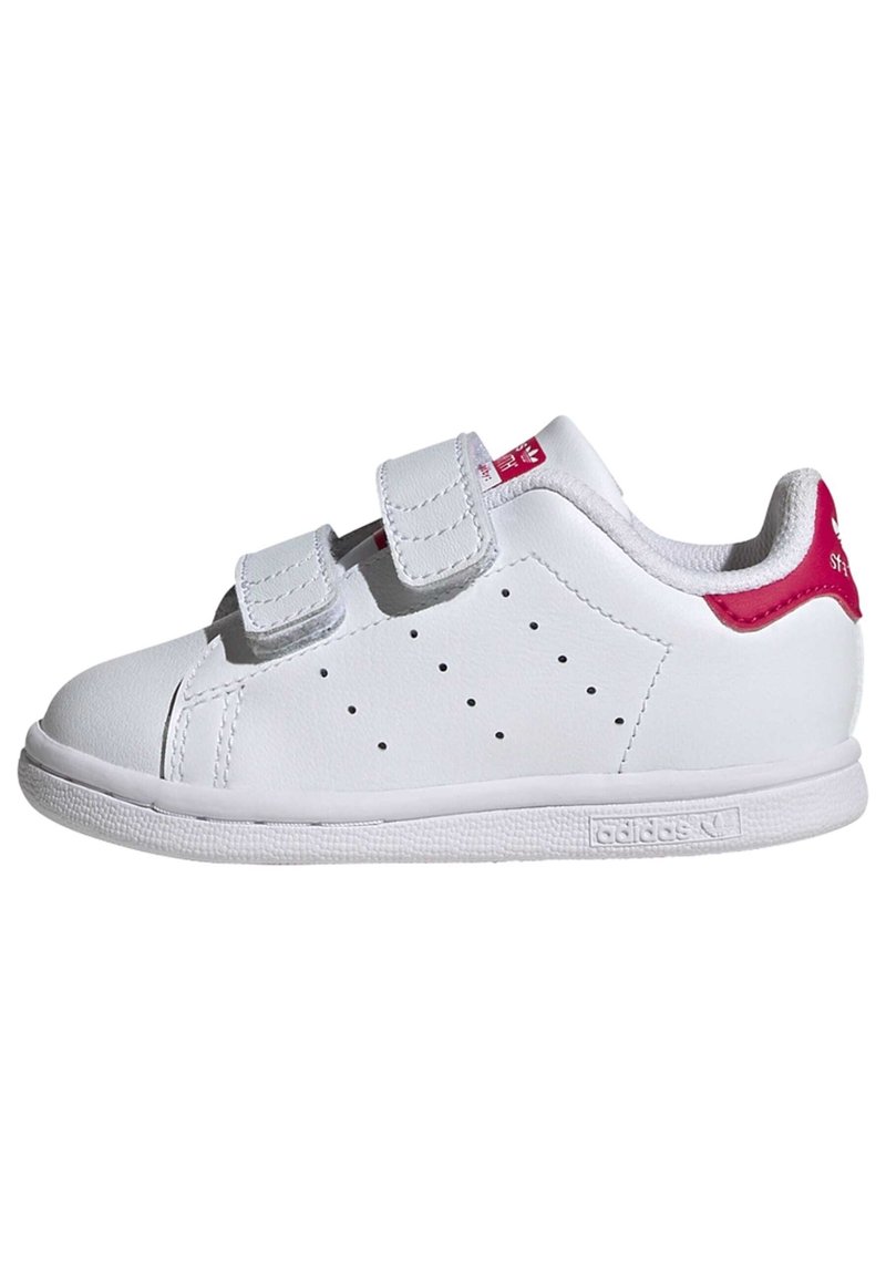 White leather sneaker with two Velcro straps, perforated detailing on the sides, and a pink accent on the heel and tongue. Rubber sole.