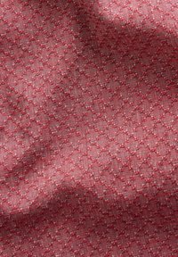 Tissu textile dans une nuance rouge présentant un motif géométrique, une texture lisse et des détails tissés fins, créant une profondeur subtile dans son apparence.