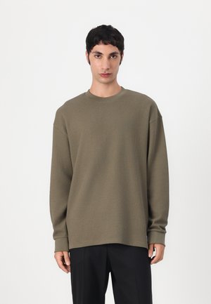 Olijfgroene geribbelde sweatshirt met een ronde hals en lange mouwen, met een relaxte pasvorm en gestikte details langs de naden.