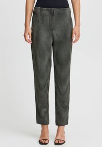 Pantalons à motif à carreaux noir et blanc avec une coupe ajustée, des jambes fuselées et une taille moyenne. Le tissu semble lisse avec un léger éclat.