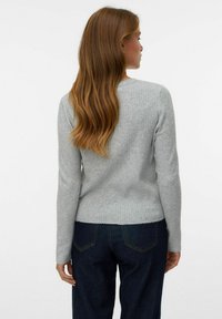Grijze geribbelde trui met lange mouwen en een ronde halslijn, gecombineerd met donkere denim jeans, die een eenvoudig, casual ontwerp laat zien.
