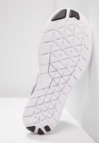Suola di una scarpa sportiva con una base in gomma bianca, caratterizzata da una superficie testurizzata e un motivo a battistrada angolare per una presa migliore. Dettagli in accento nero visibili.