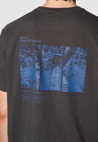 Czarny bawełniany t-shirt z niebieskim nadrukiem map i tekstu, z detalami "OFF DUTY GEAR" oraz "HIGH ALTITUDE LOW OPENING".