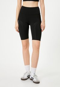 Svarta sportiga cykelbyxor med hög midja, med texturerade prickmönster längs sidorna. Tillverkade av stretchigt och lätt material.