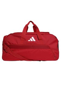 Bolsa de viaje roja con dos asas y una correa de hombro desmontable, que presenta un logo blanco, un bolsillo de malla y cierre de cremallera. Tejido duradero.
