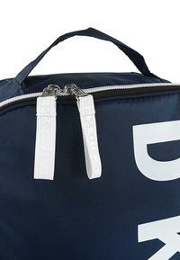 Bolsa de lona azul marino con cremallera blanca, tiradores dobles y gran marca blanca. Cuenta con un asa resistente para facilitar el transporte.