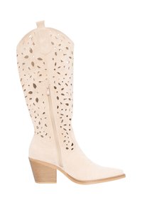 Beige suède laarzen tot halverwege de kuit met een bloemenpatroon van uitsnijdingen, ritssluiting aan de zijkant, spits toelopende neus en gestapelde houten blokhak.