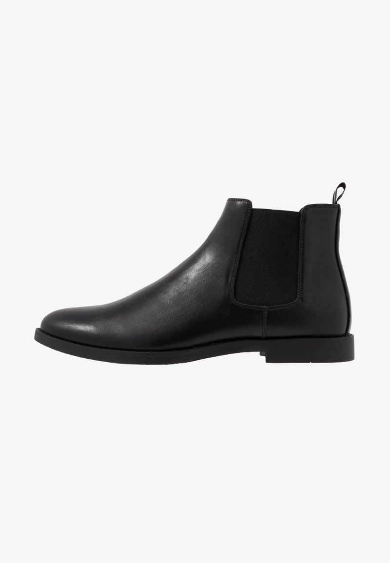 Bottine Chelsea en cuir noir avec panneaux latéraux élastiques, bout arrondi, petit talon et languette à l'arrière.